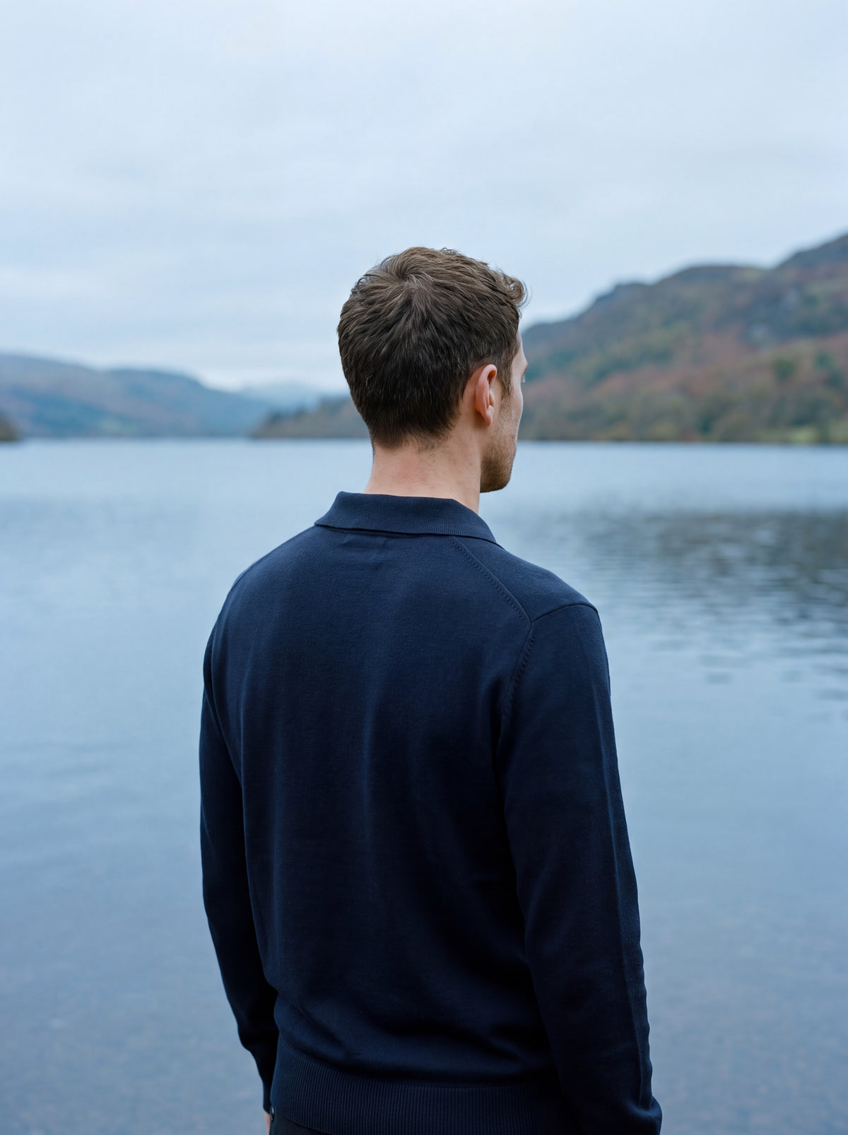 Francesco Bellani Solferino knitted polo worn from behind, looking out over still lake water