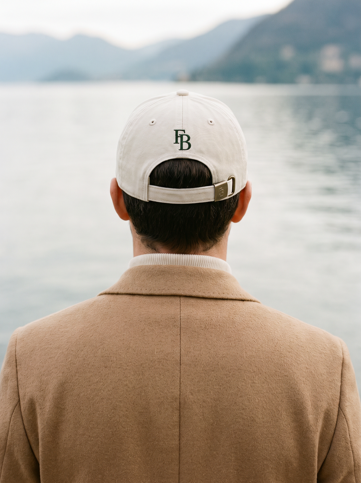 Francesco Bellani accessories — the Rapallo cap seen from behind, FB monogram at the back, on a Lake Como waterfront
