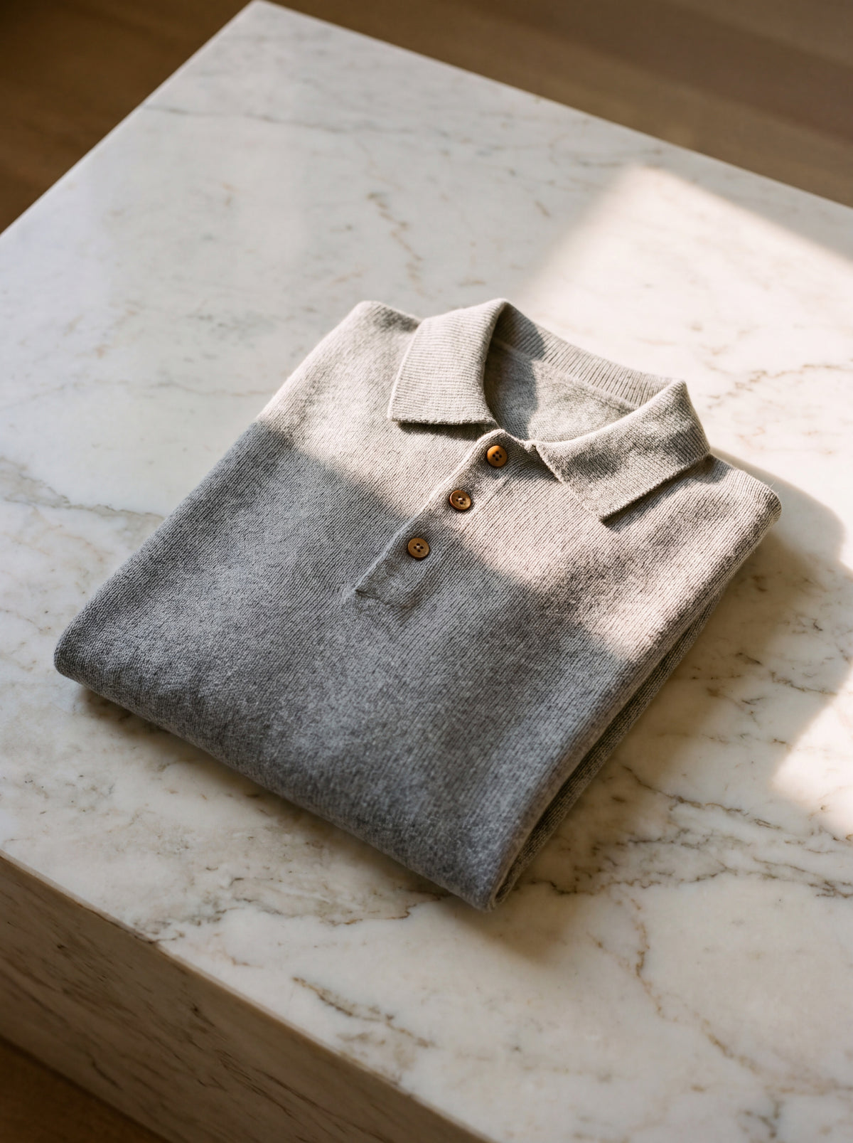 Francesco Bellani Brera cashmere polo folded on pale marble, collar and hand-finished wooden buttons visible