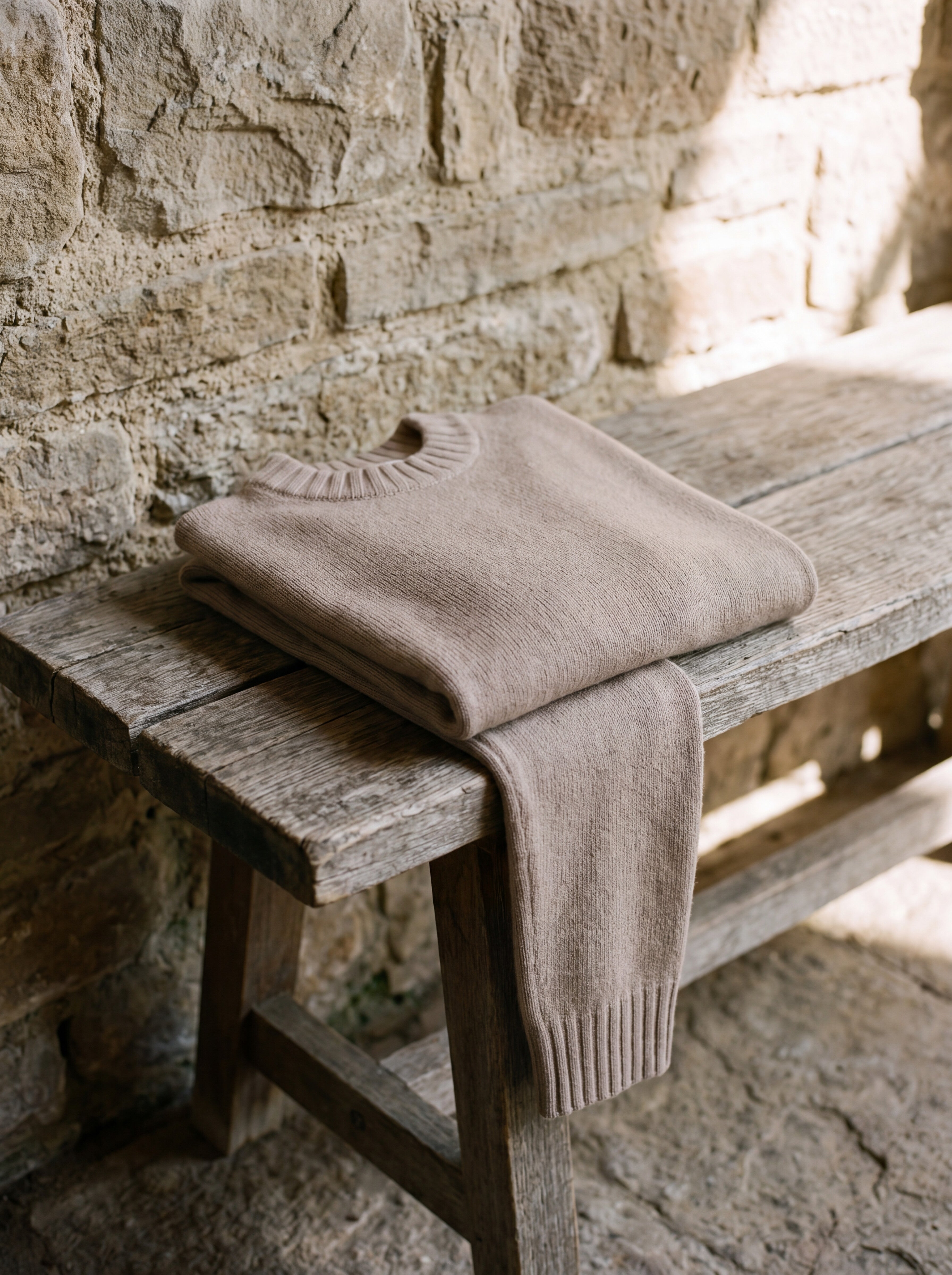 Francesco Bellani Navigli wool pullover folded across an aged wooden bench beside a stone wall