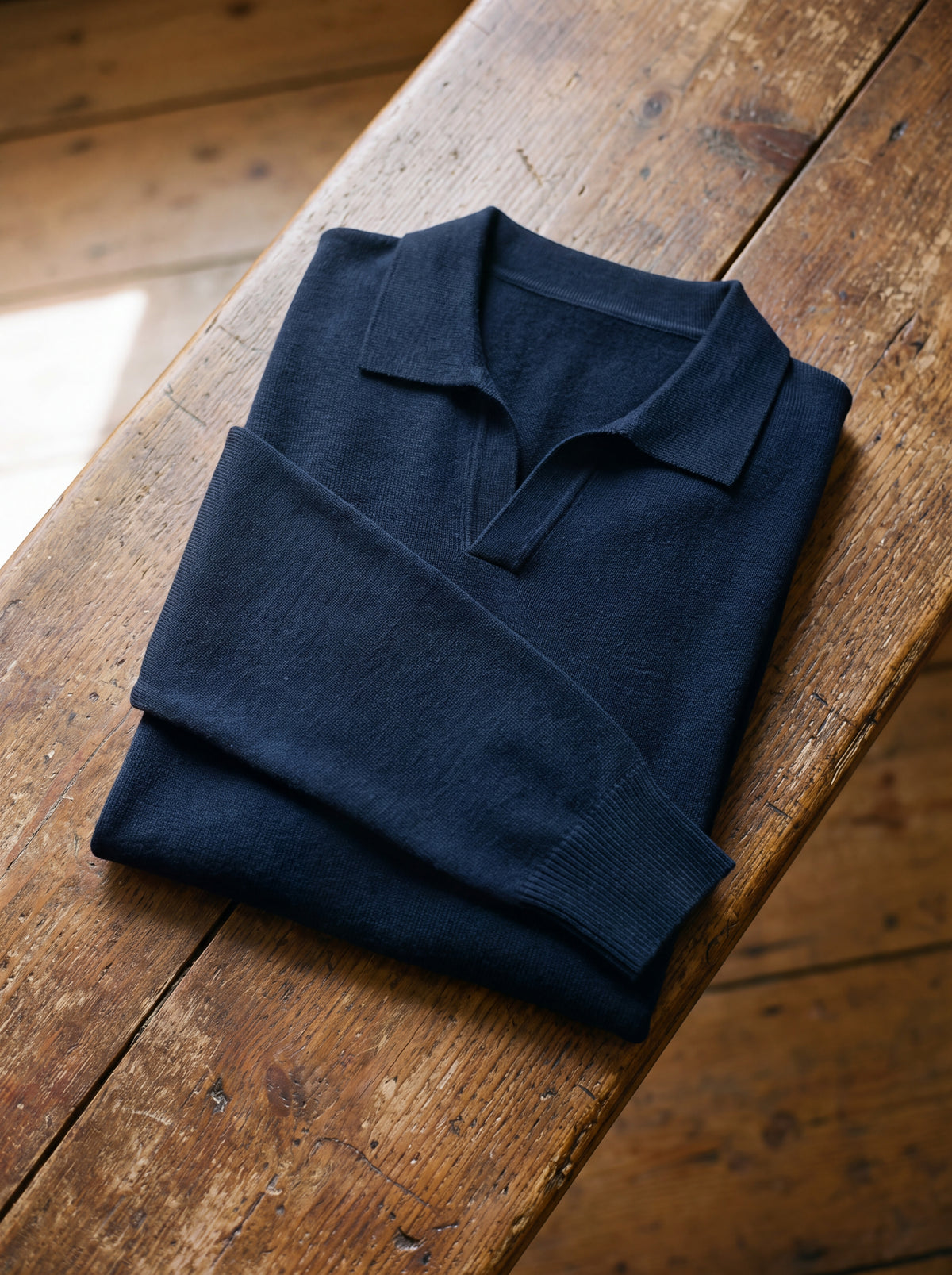 Francesco Bellani Solferino knitted polo laid flat on an aged wooden bench, shallow V collar visible