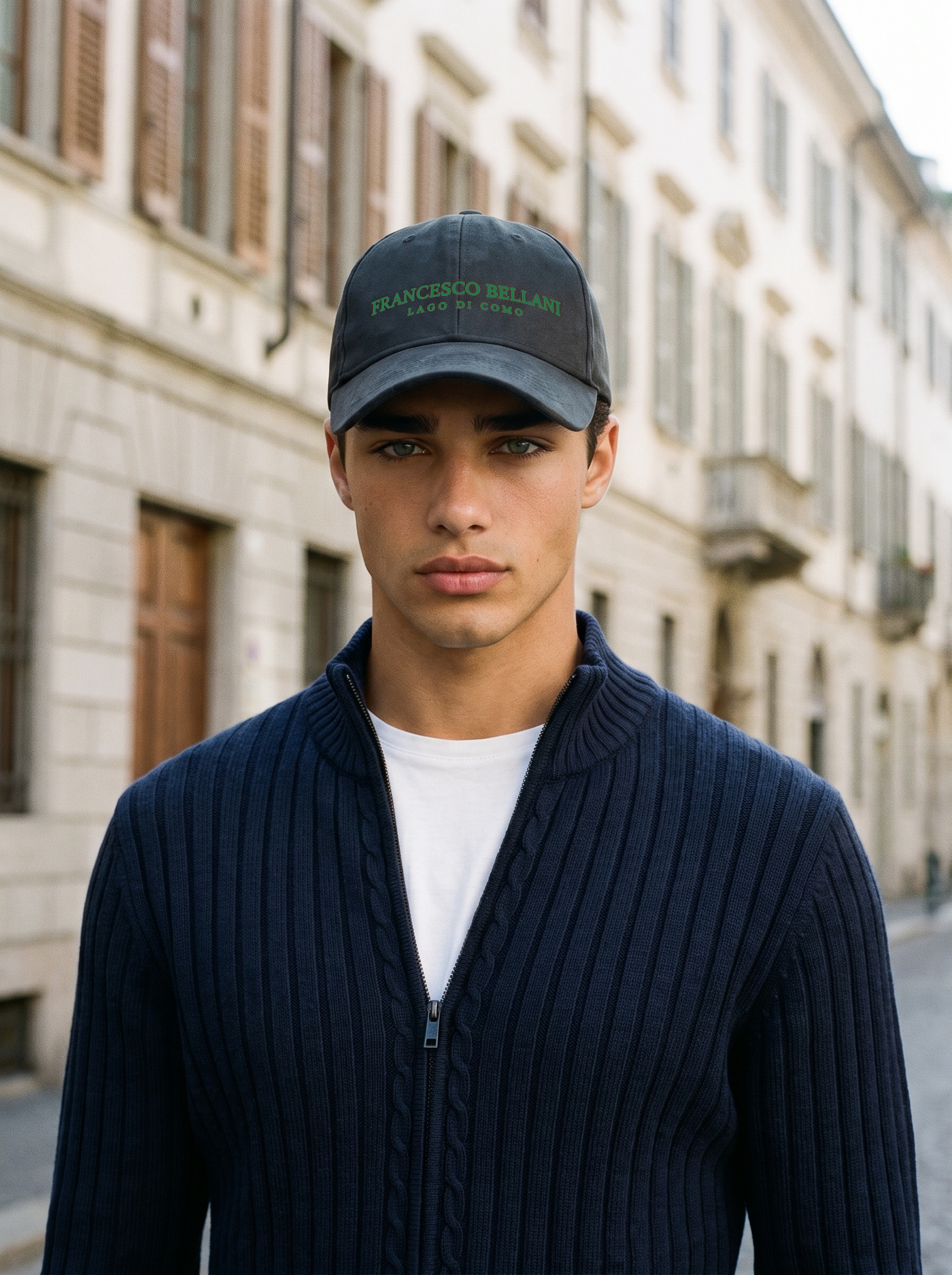 Rapallo cap in Black worn on a European street with a navy ribbed zip cardigan