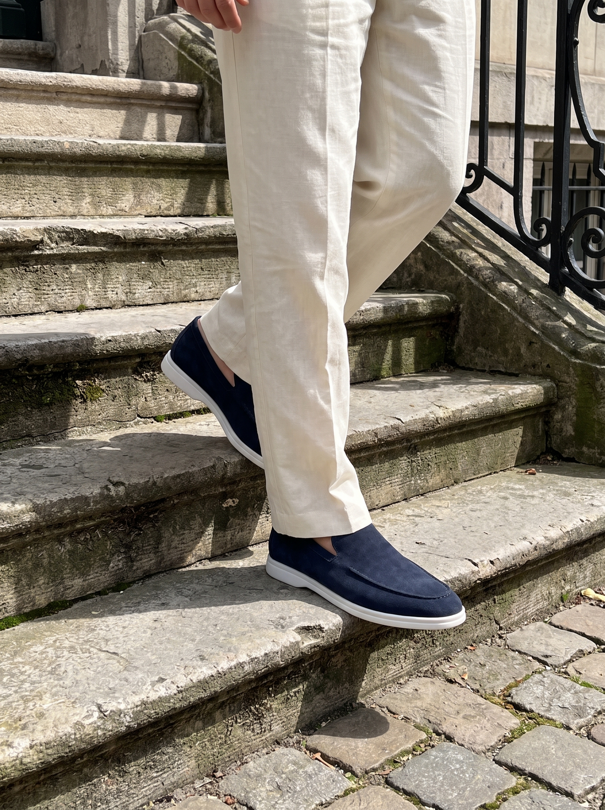 Man wearing deep sea blue suede loafers with cream linen trousers on stone steps — Francesco Bellani Bellagio