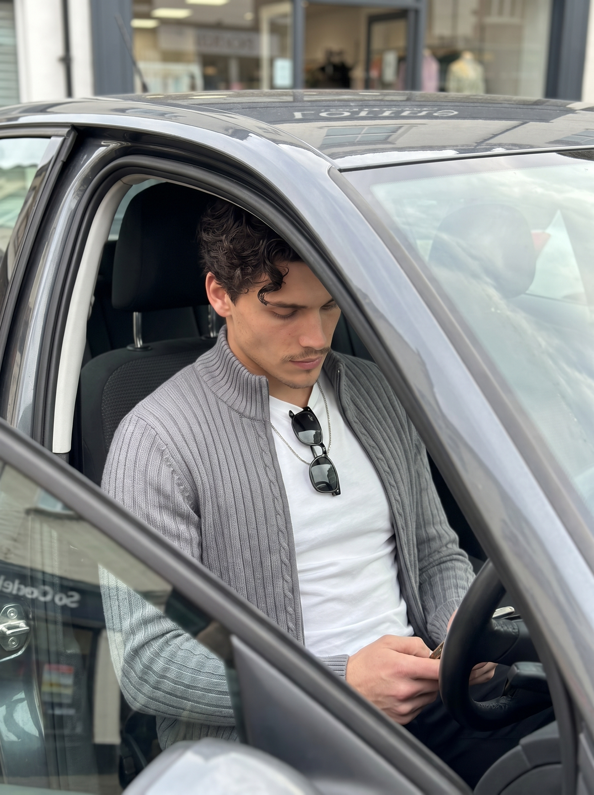 Man wearing an ash grey cable-knit zip-through in the driver's seat of a car — Francesco Bellani Aosta