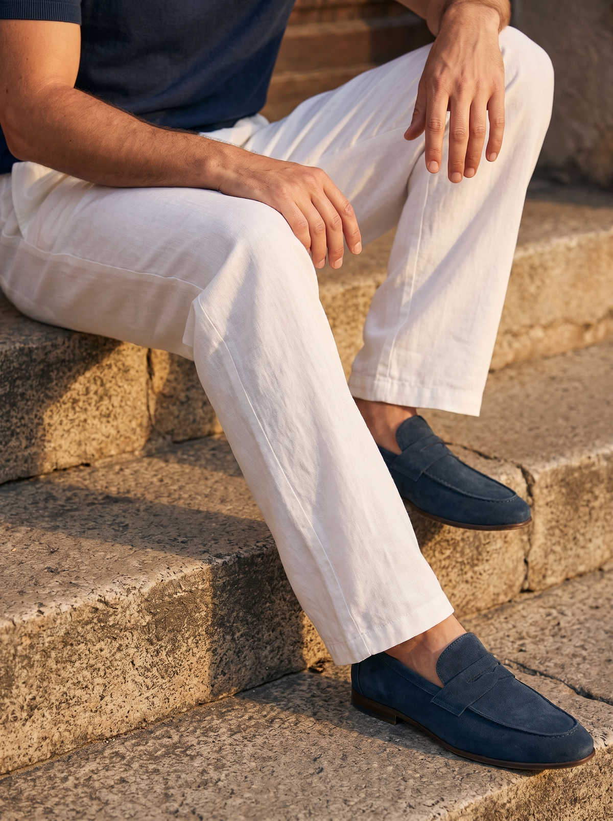 Waistband and pleat detail on natural linen trousers, seated on stone steps — Francesco Bellani Portofino